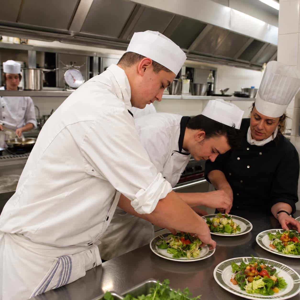 Jeunes en formation cuisine préparant des assiettes avec une formatrice